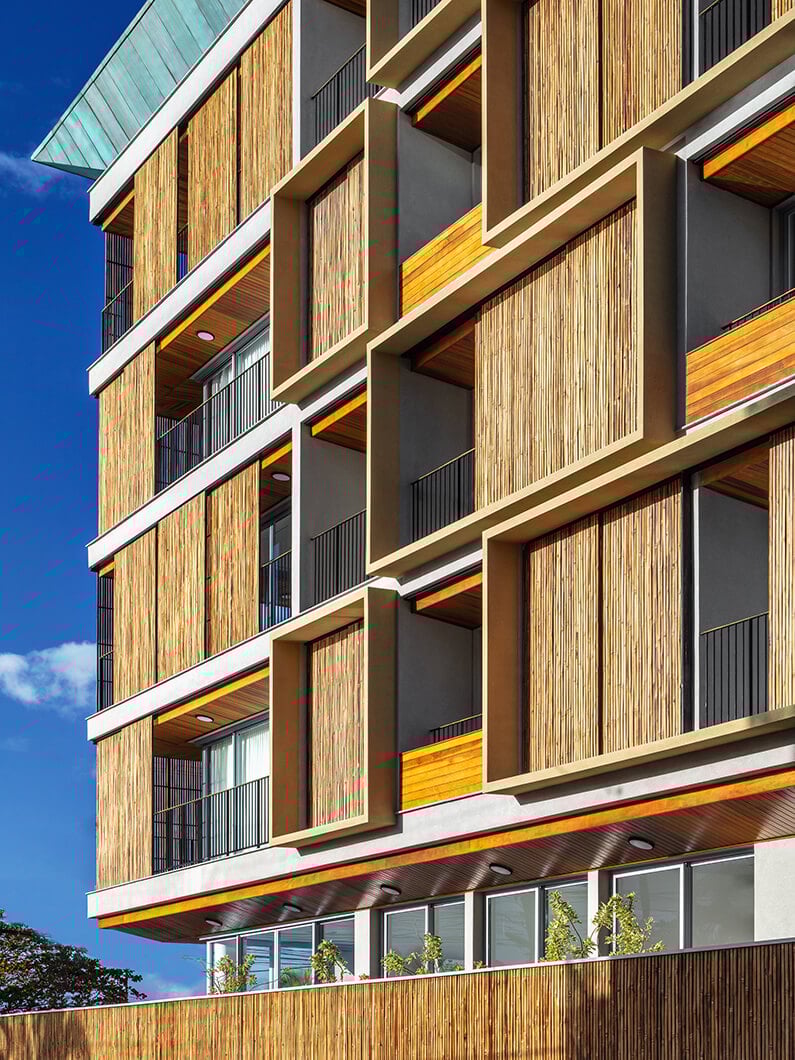 Modern building facade with wood panel details against a clear blue sky.