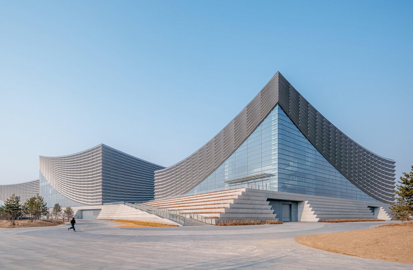 Modern architectural design with sleek curves and glass facade under clear blue sky.