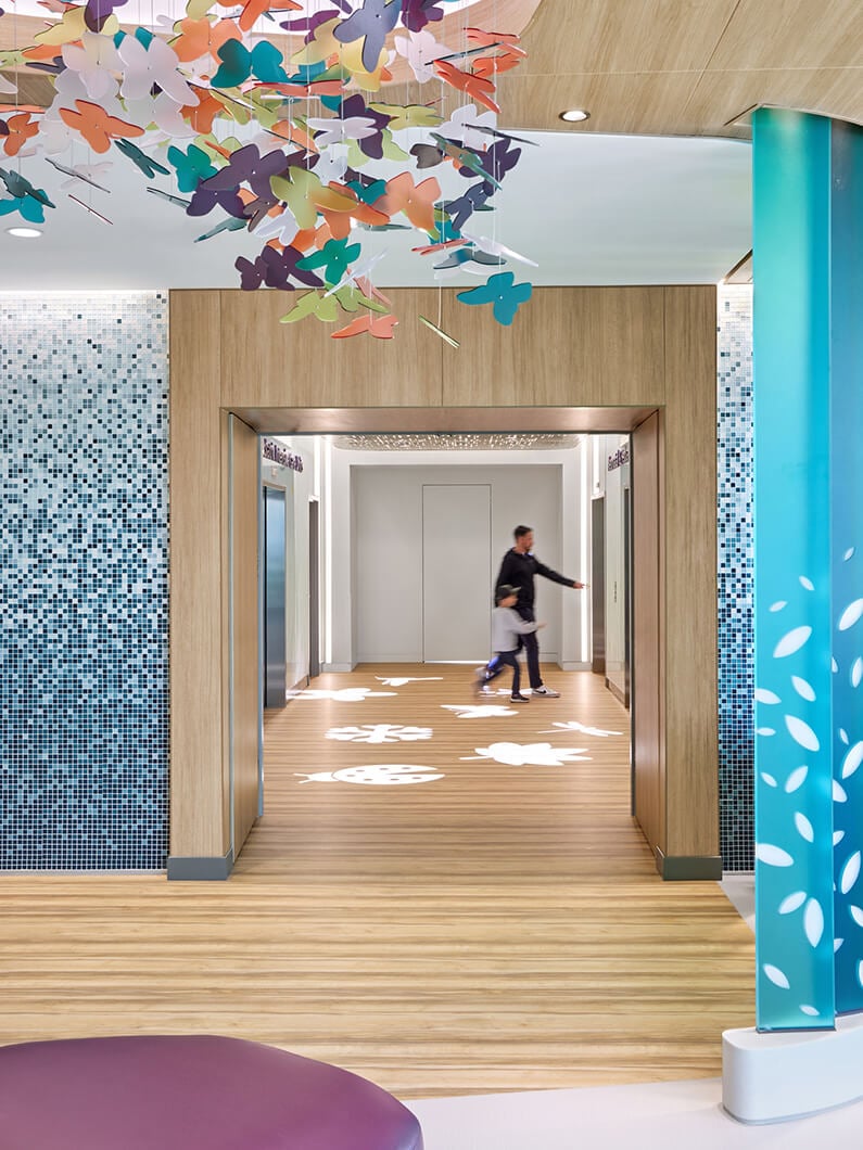 Colorful butterfly ceiling decor in a modern lobby with wood accents and mosaic walls.