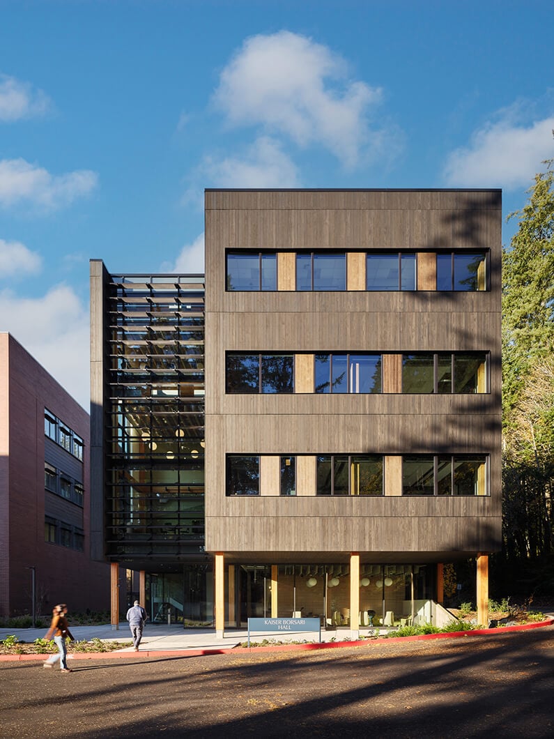 Modern building with wooden facade and glass elements under a blue sky.