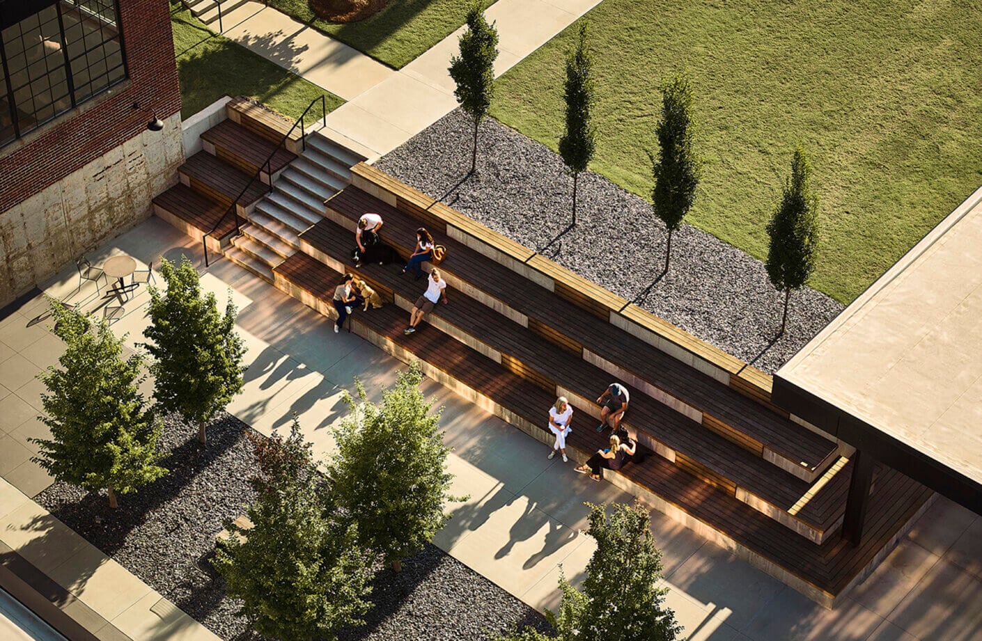 Modern outdoor seating area with people and greenery from above.