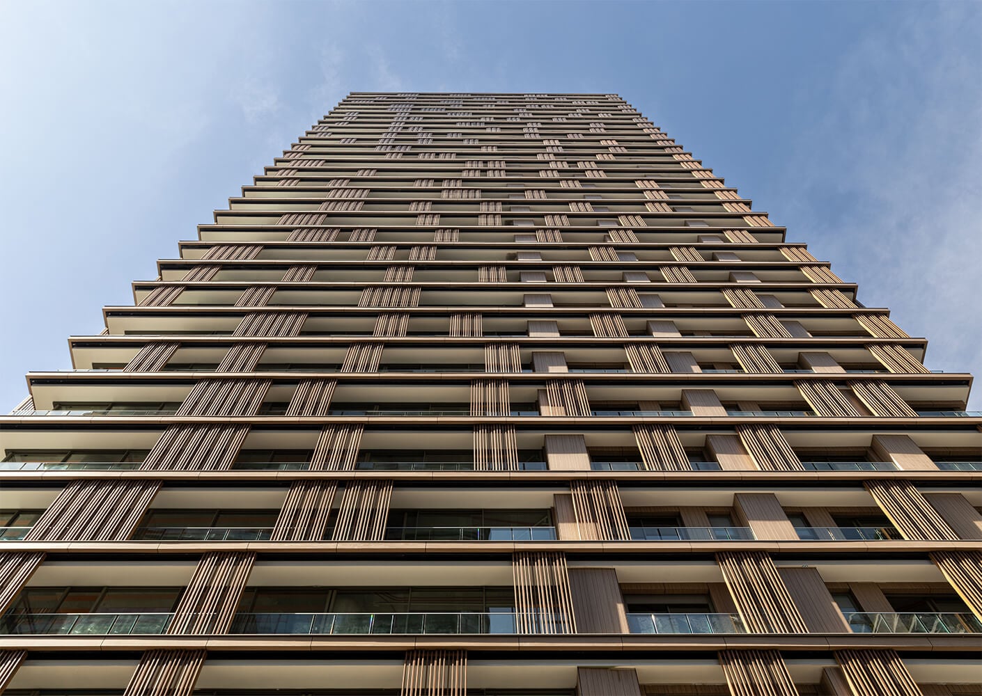 Modern skyscraper with wood panel facade under clear sky.