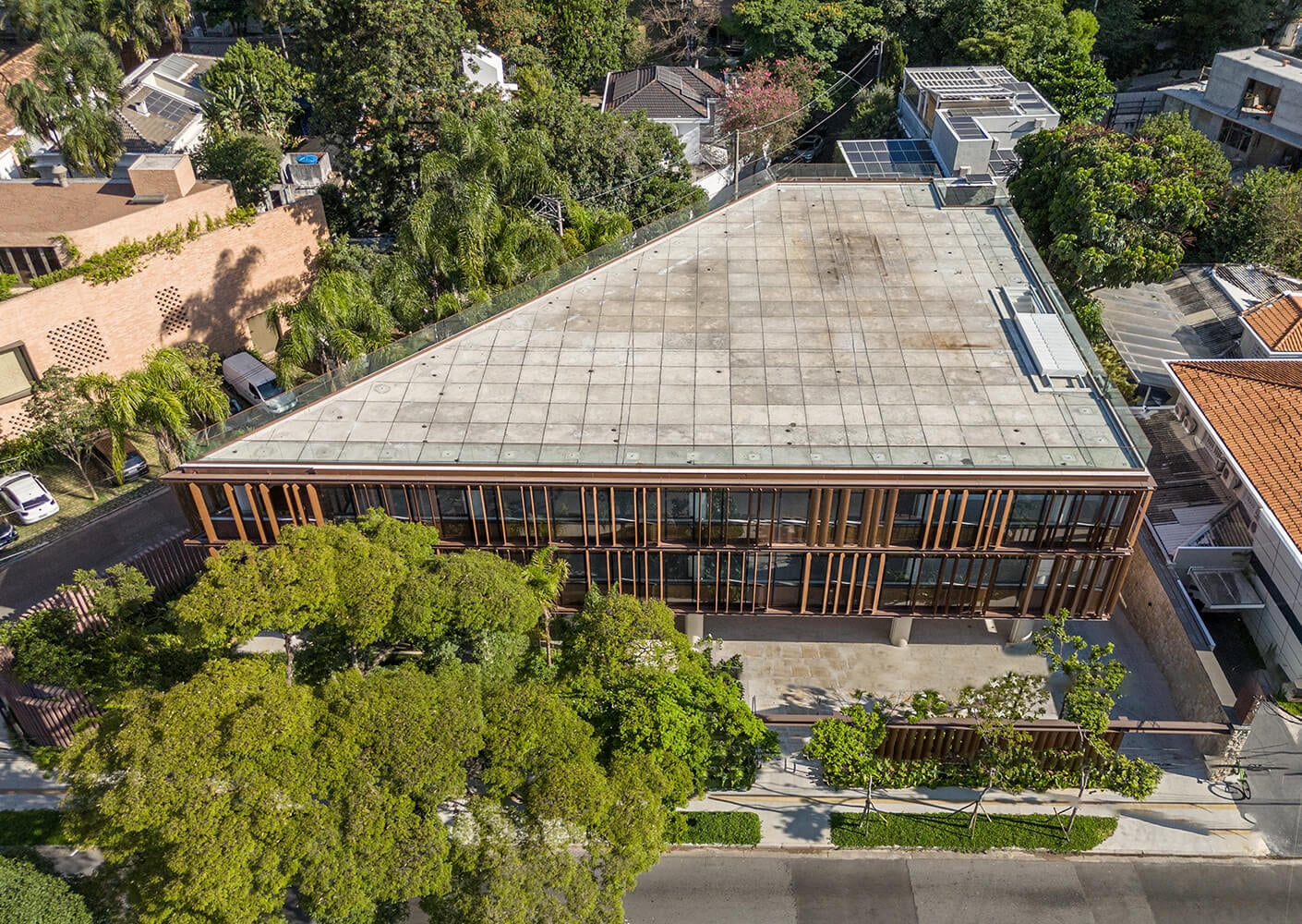 Modern triangular building with lush greenery and solar panels on roof.