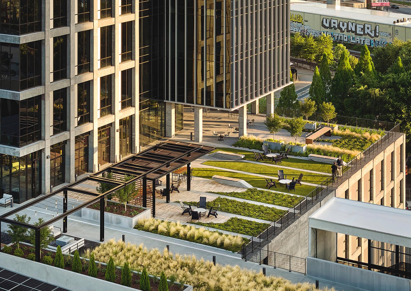 Modern urban rooftop garden with seating and green spaces on city building.