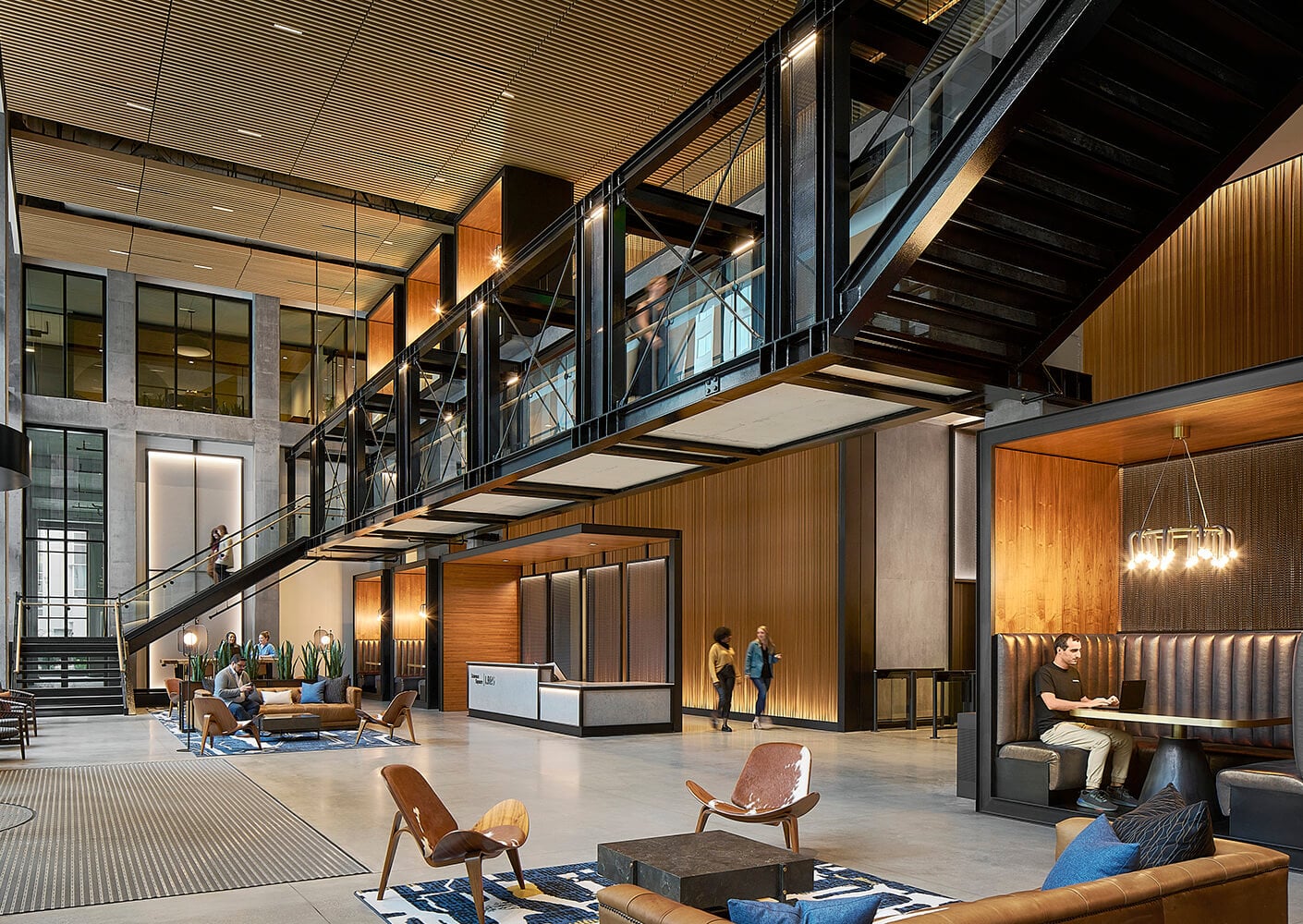 Modern lobby with wood accents, seating, and a mezzanine walkway.
