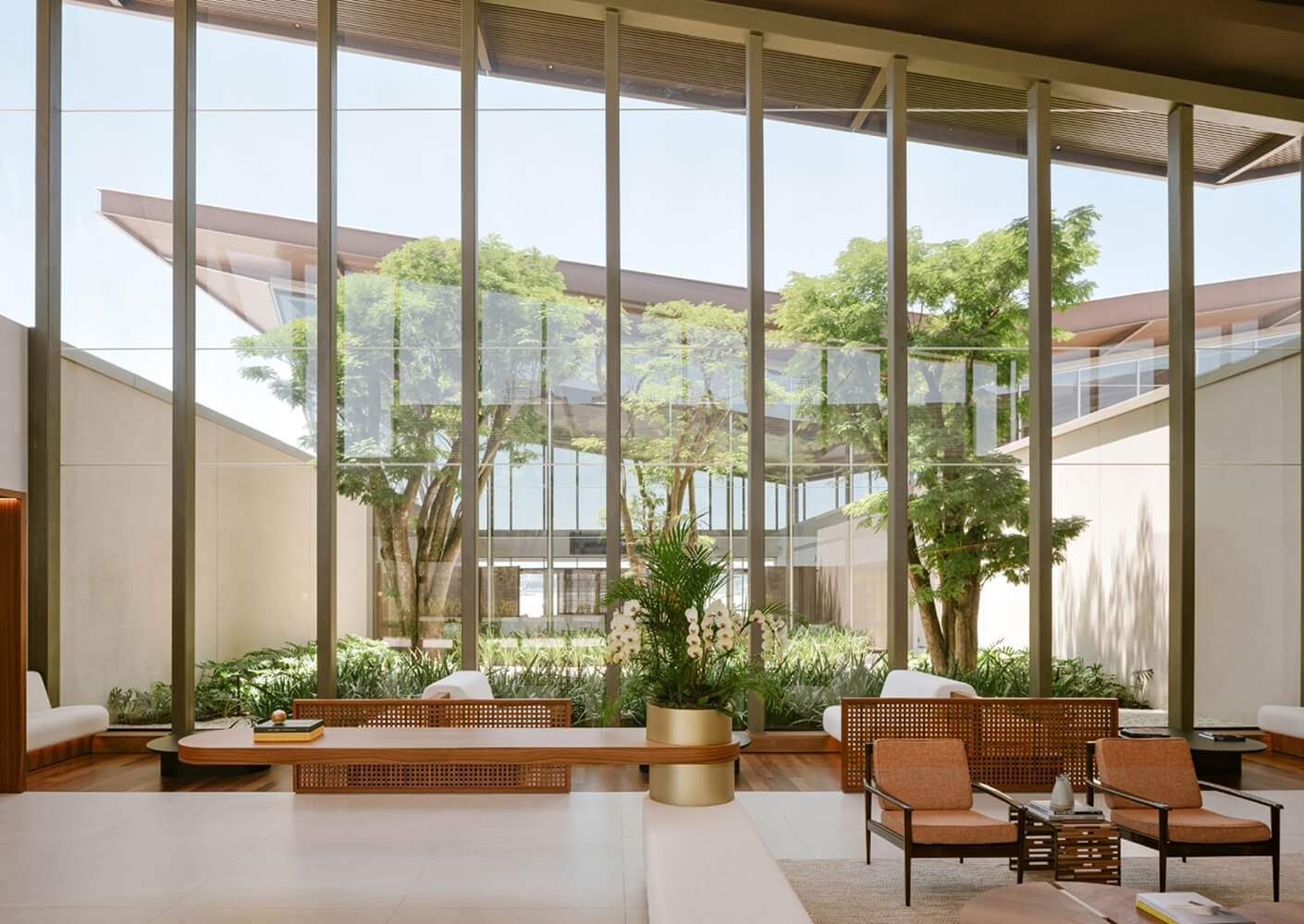 Modern lobby with glass walls, greenery, and stylish seating.