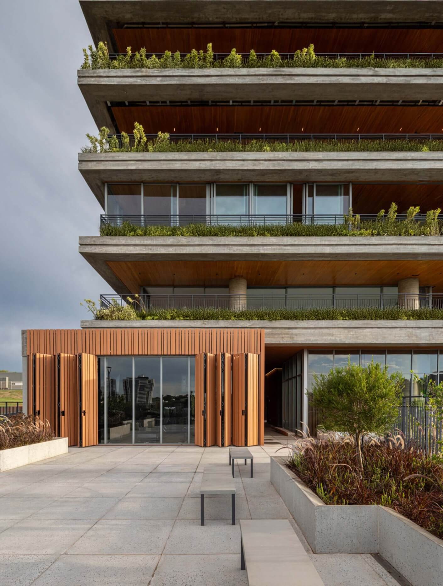 Modern multi-story building with greenery and wooden accents.