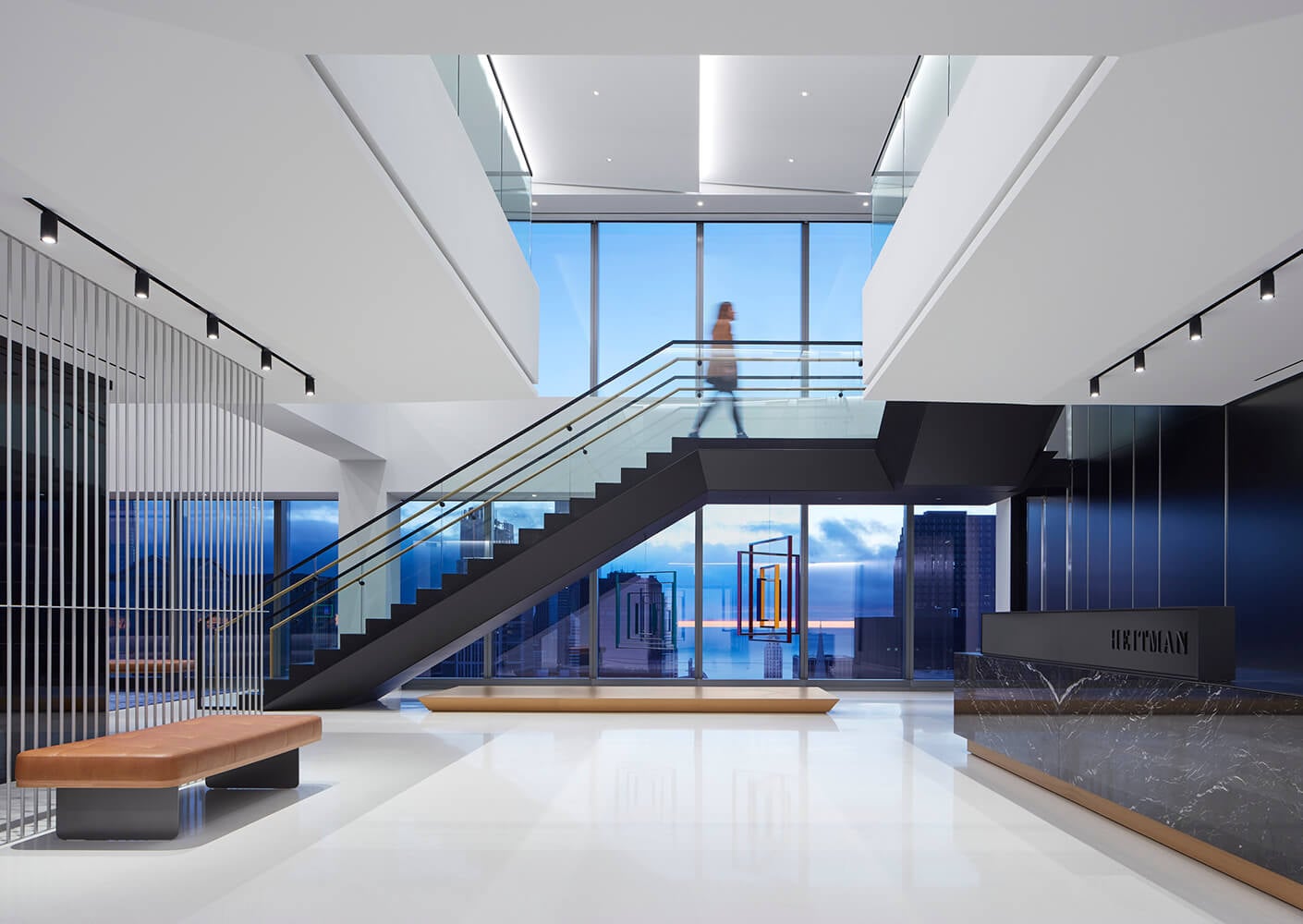 Modern office lobby with floating staircase and city view.