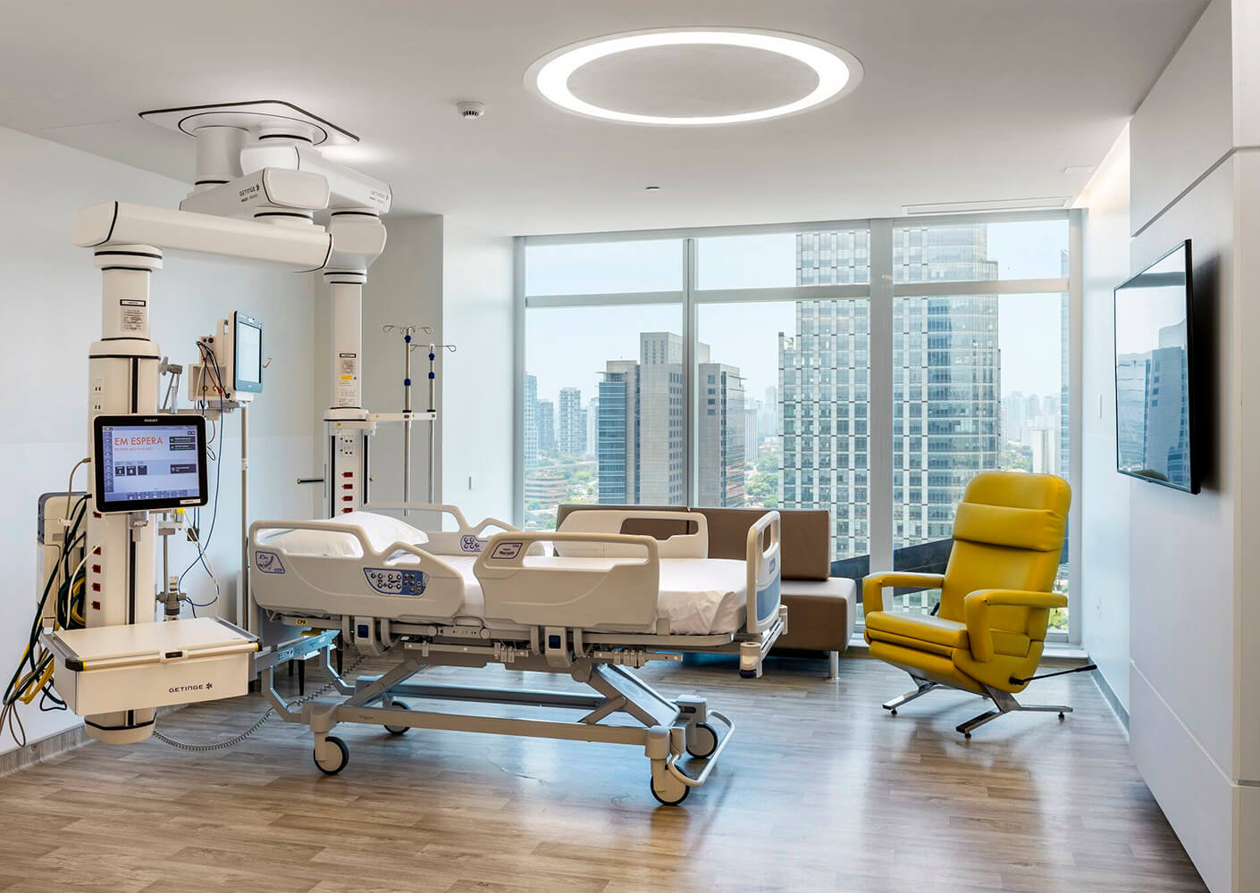 Modern hospital room with advanced medical bed and city view.