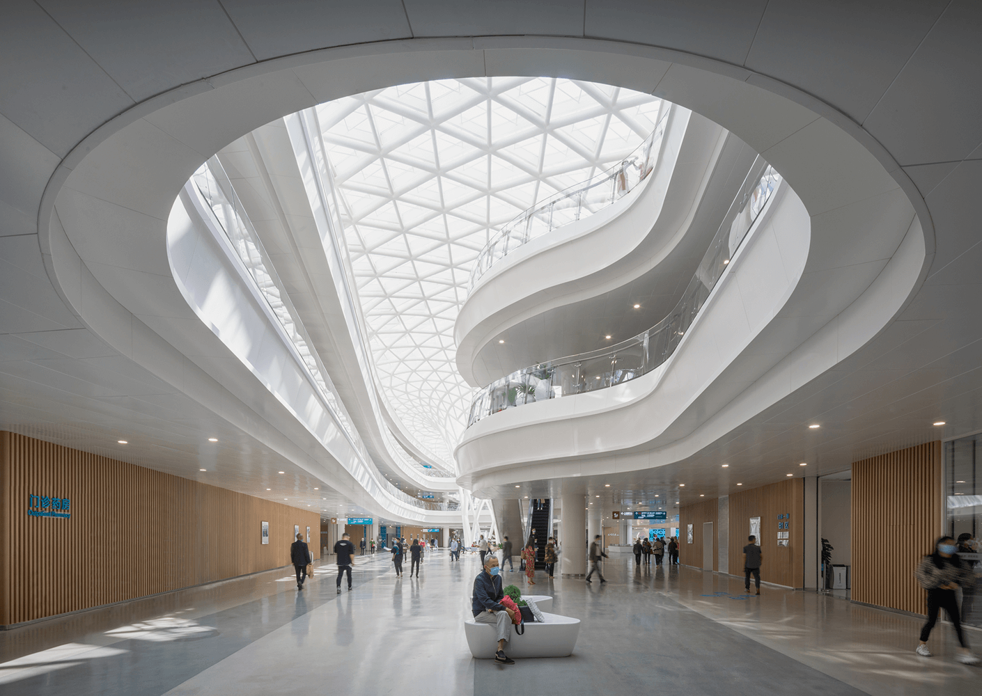 Modern architectural space with people walking under curved ceiling and natural light.
