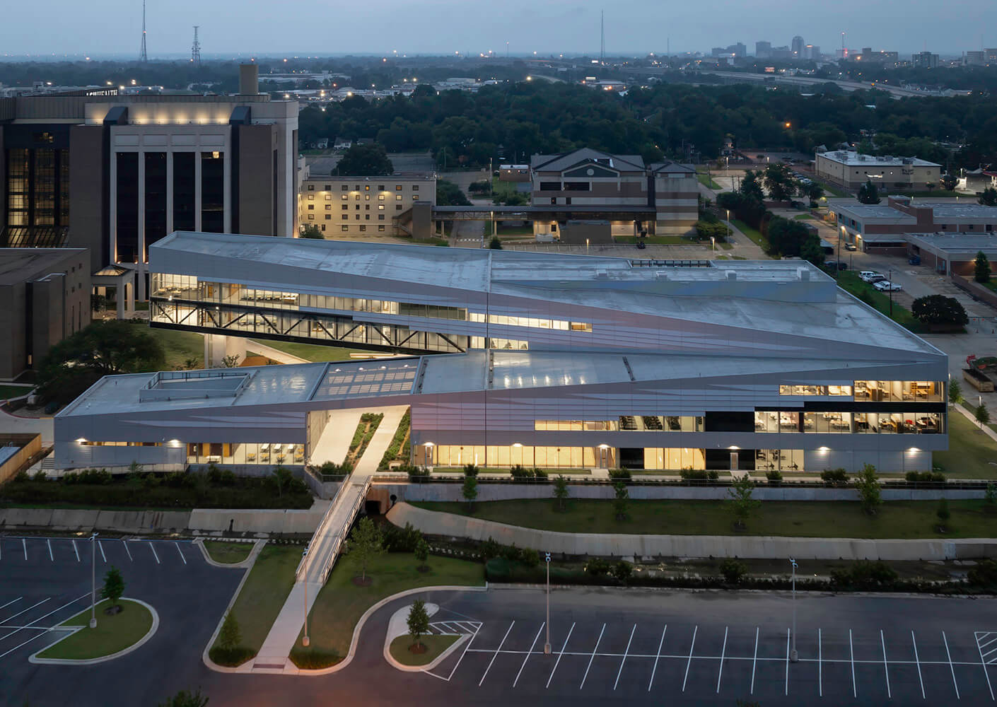 Modern architectural building at dusk with city skyline background.