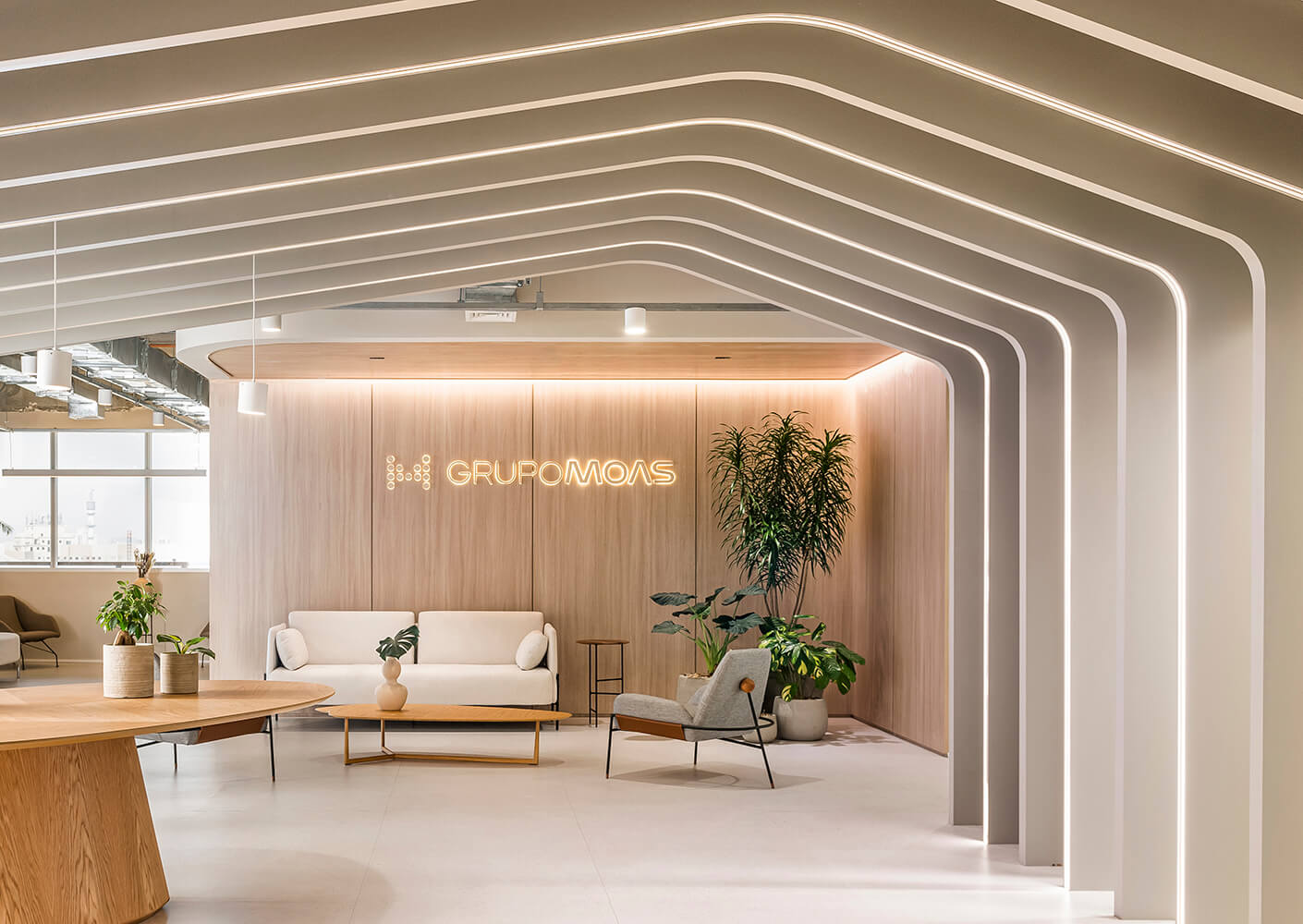 Modern office lobby with sleek design and seating area, featuring Grupo Moas branding.