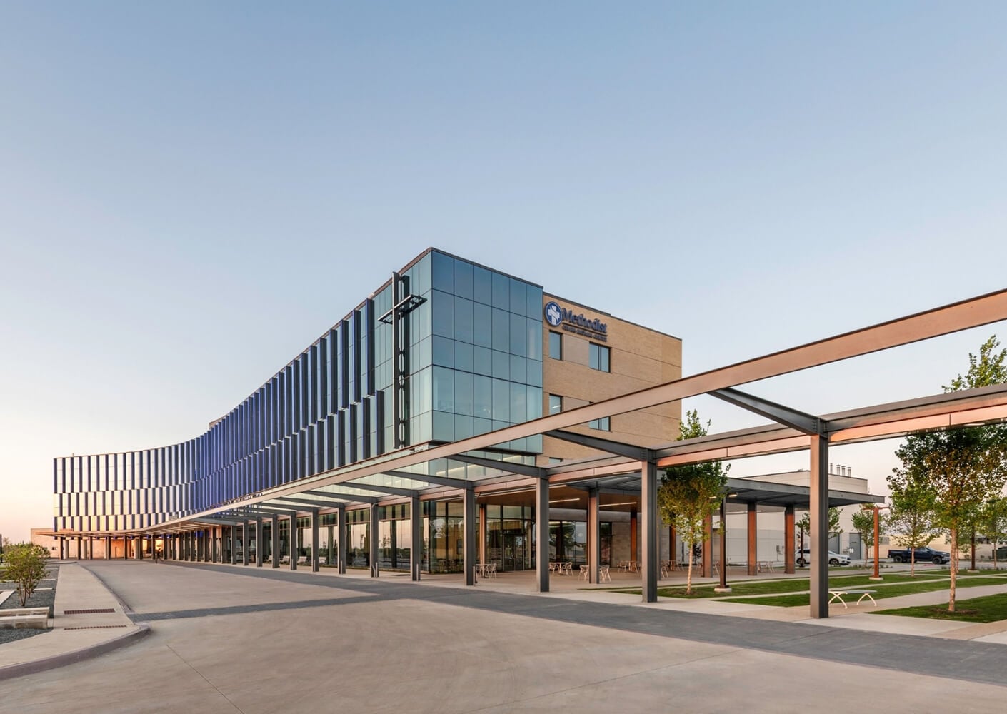 Modern hospital building exterior with glass facade under clear sky.