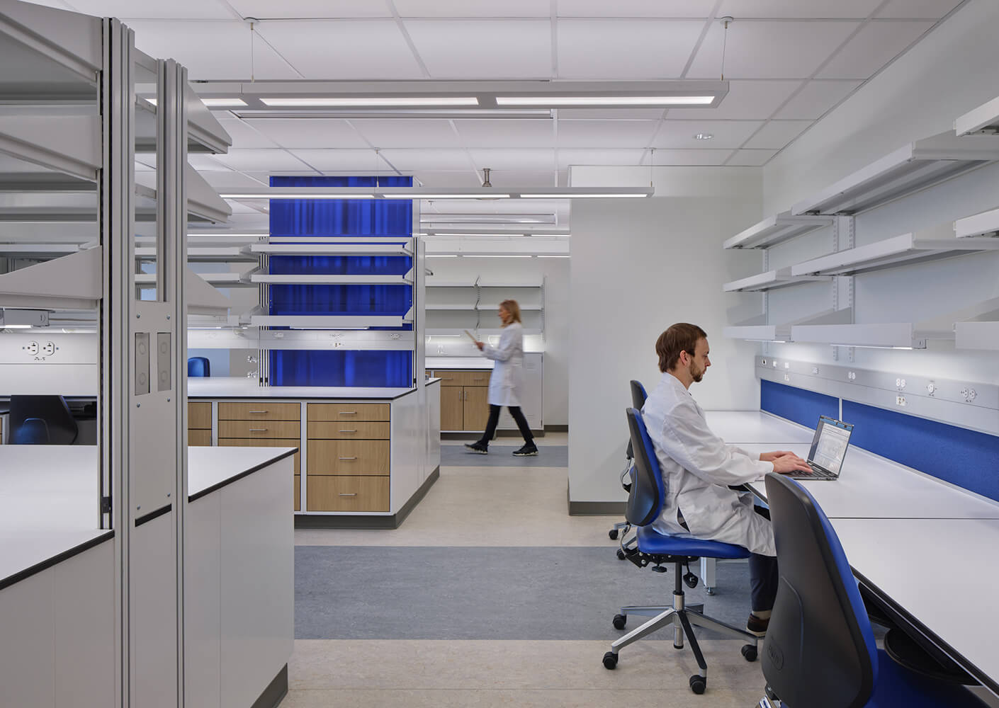 Laboratory researchers in modern lab setting with computers and shelves.