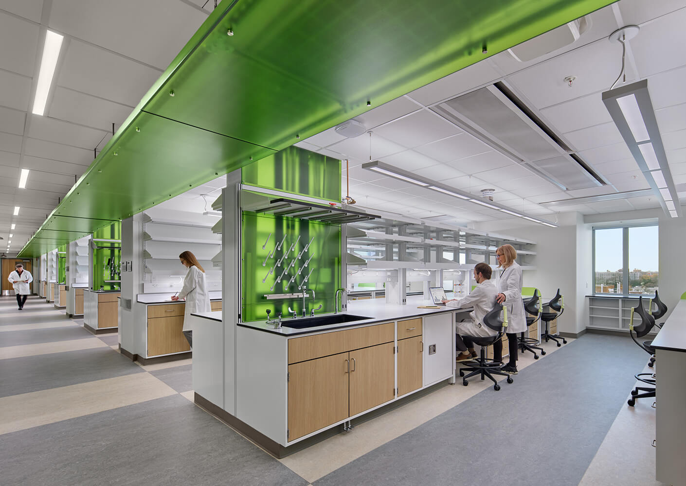 Modern laboratory with scientists in white coats working under green accents.