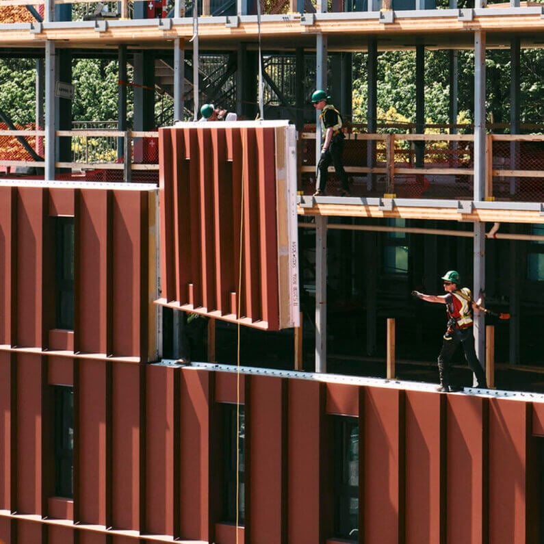 Construction workers installing a large panel on a building site.