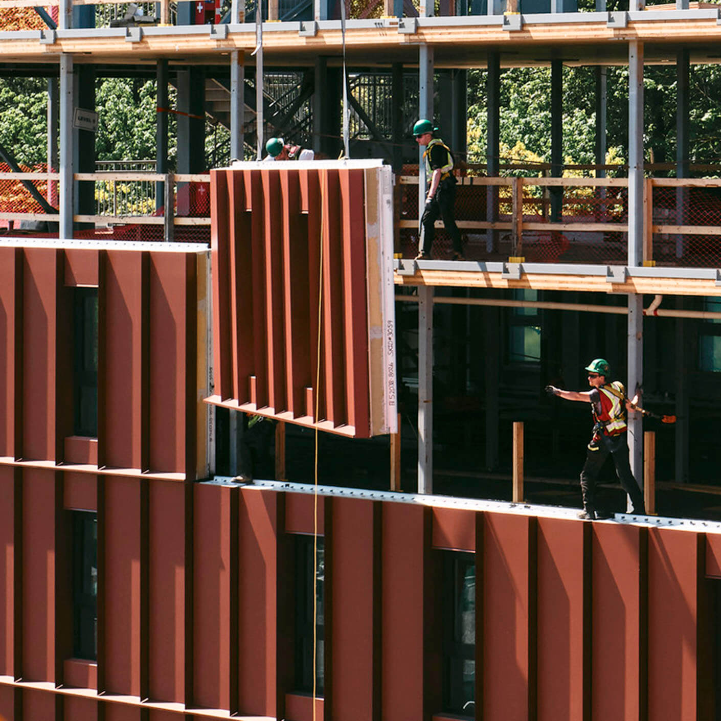 Construction workers installing a large panel on a building site.