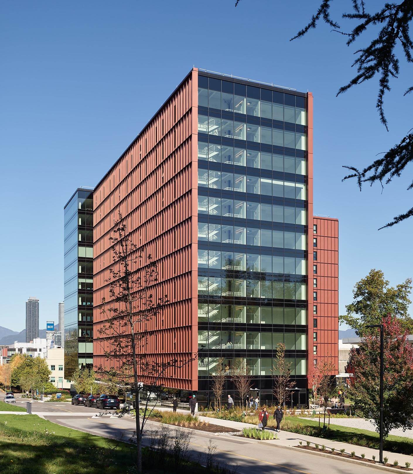 Modern red office building with glass facade under a clear blue sky.