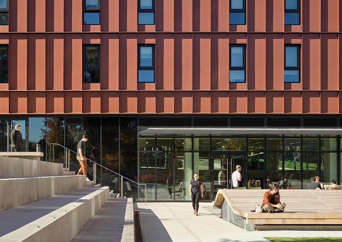 Modern building exterior with people walking and sitting outside.