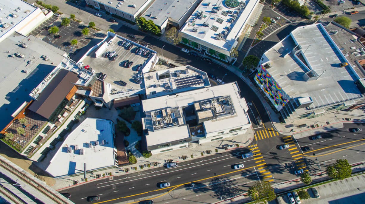 Aerial view of urban buildings and street with cars and parking lots.