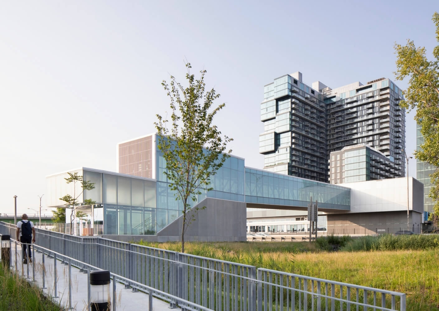 Modern glass bridge and building with green space.