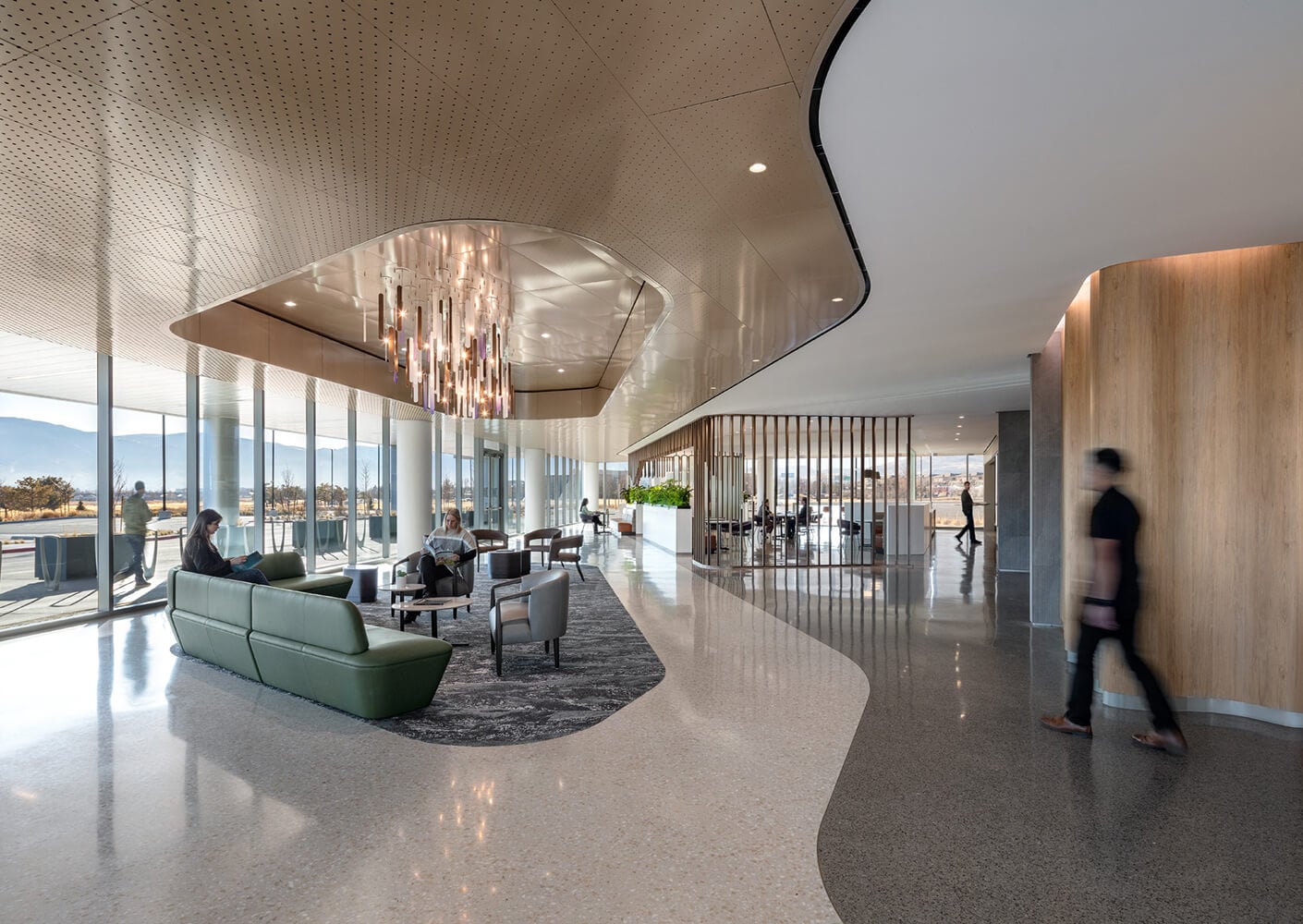 Modern office lobby with seating, chandelier, and large windows with scenic views.