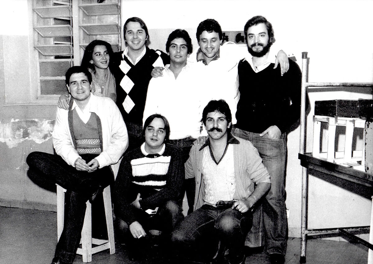Group of young adults in a vintage black and white classroom photo.