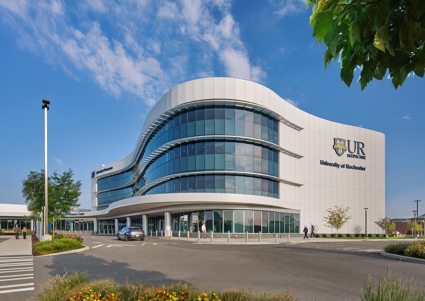 Modern medical building with curved glass facade under blue sky.