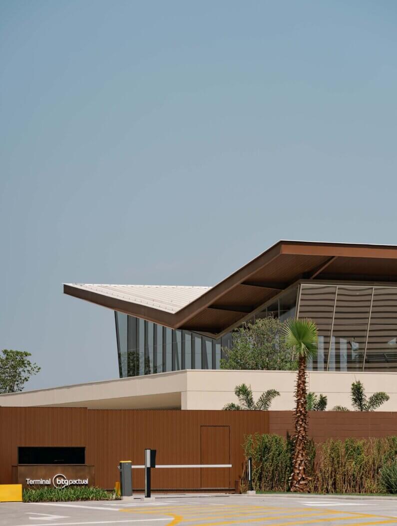 Modern architecture with a V-shaped roof at a terminal surrounded by greenery.