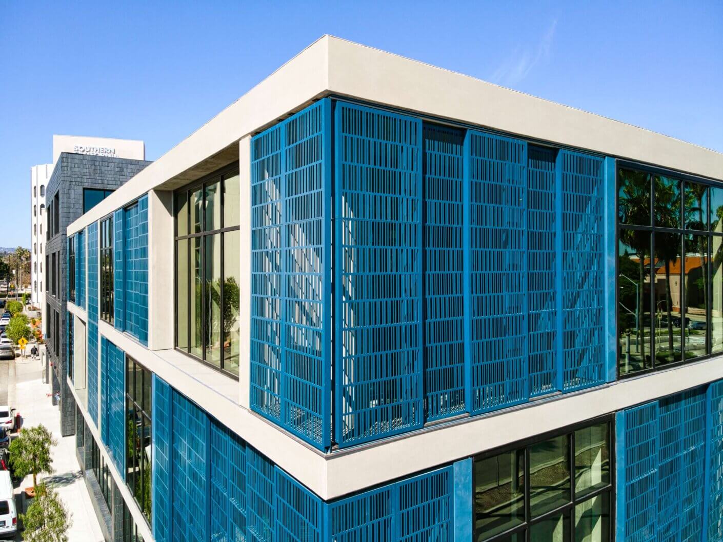Modern blue office building exterior with glass windows and clear sky.