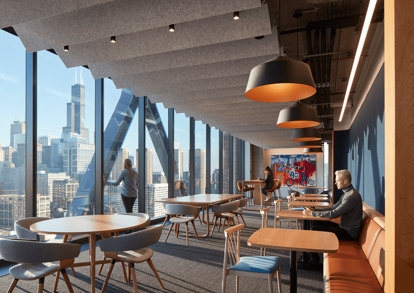 Modern office lounge with city skyline view and people working.