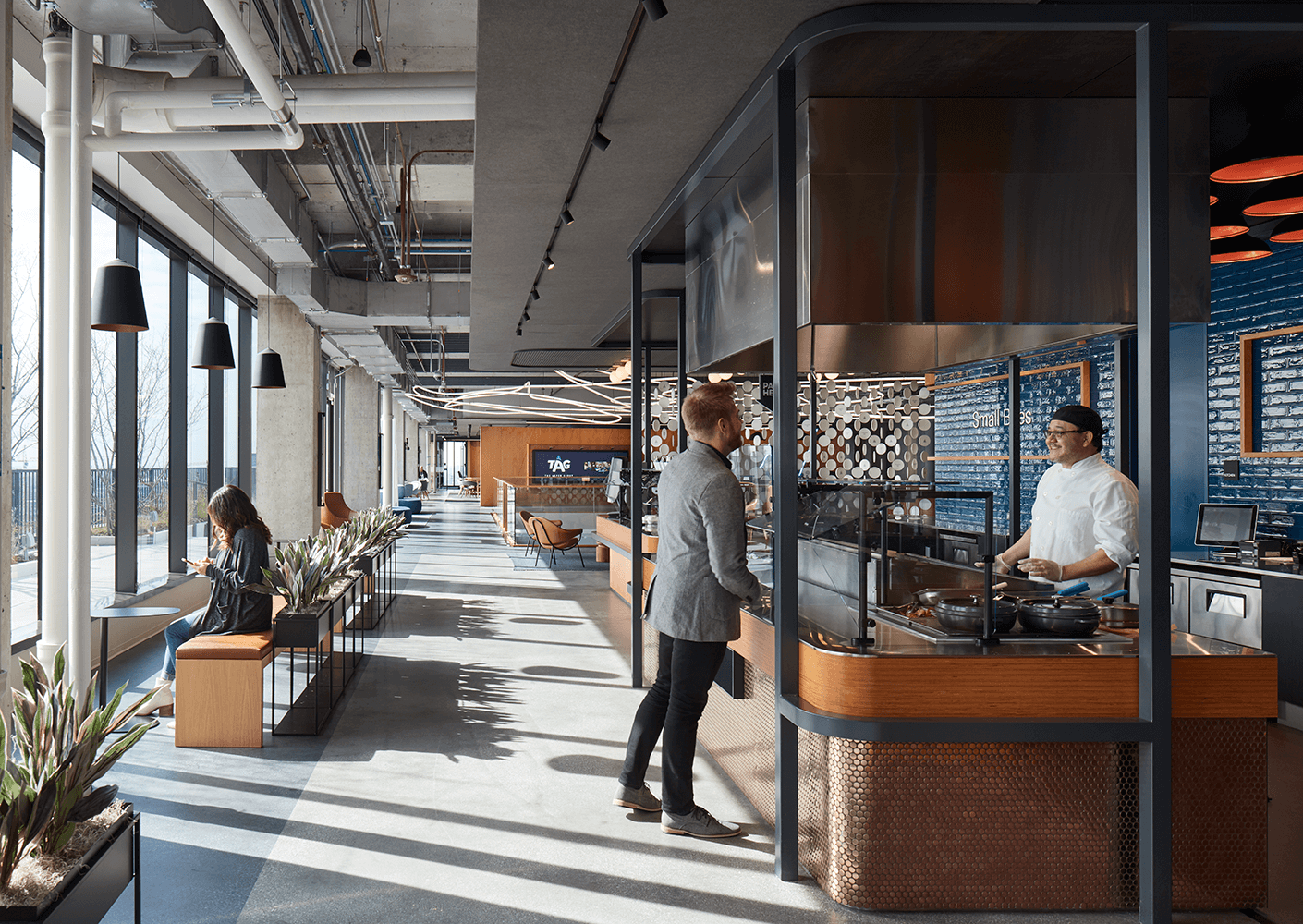 Modern office interior with people interacting in communal kitchen space.