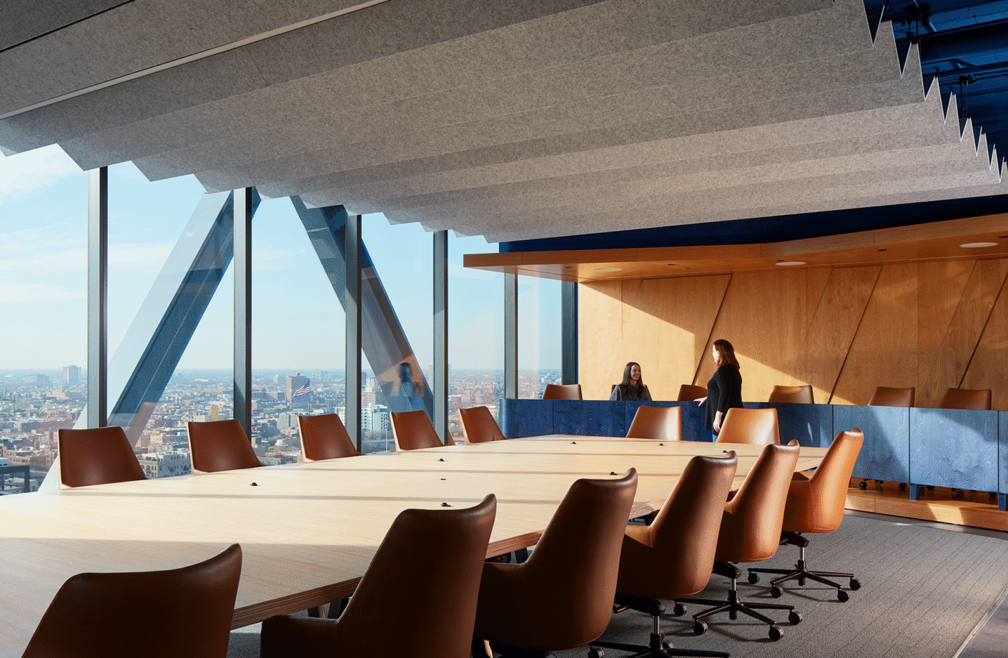 Modern conference room with a city view and brown chairs around a large table.