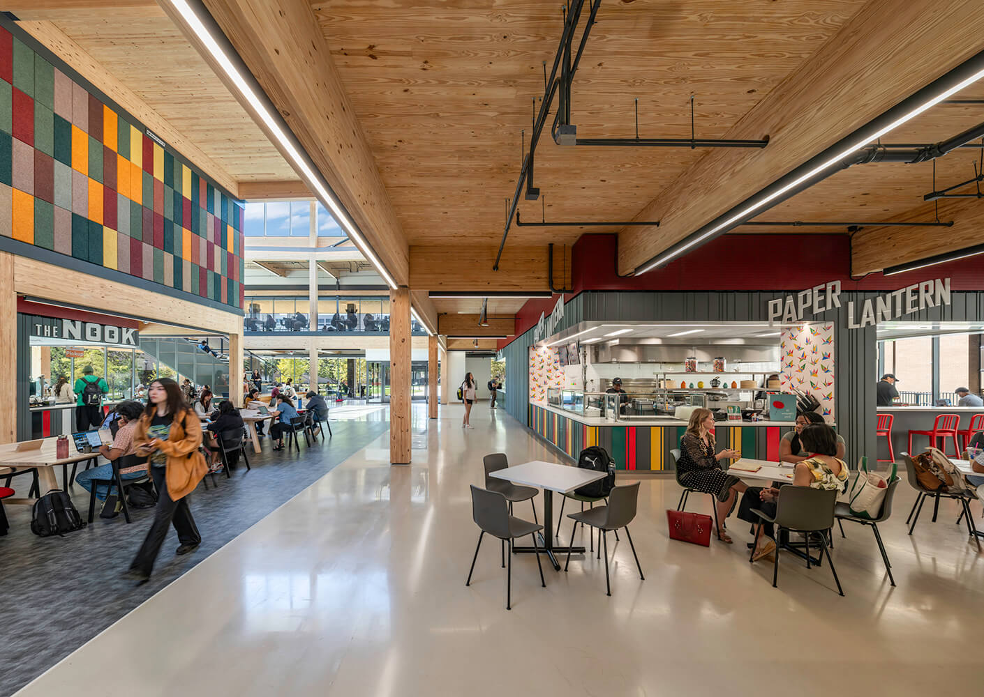 Modern cafeteria with colorful decor and people dining at tables.