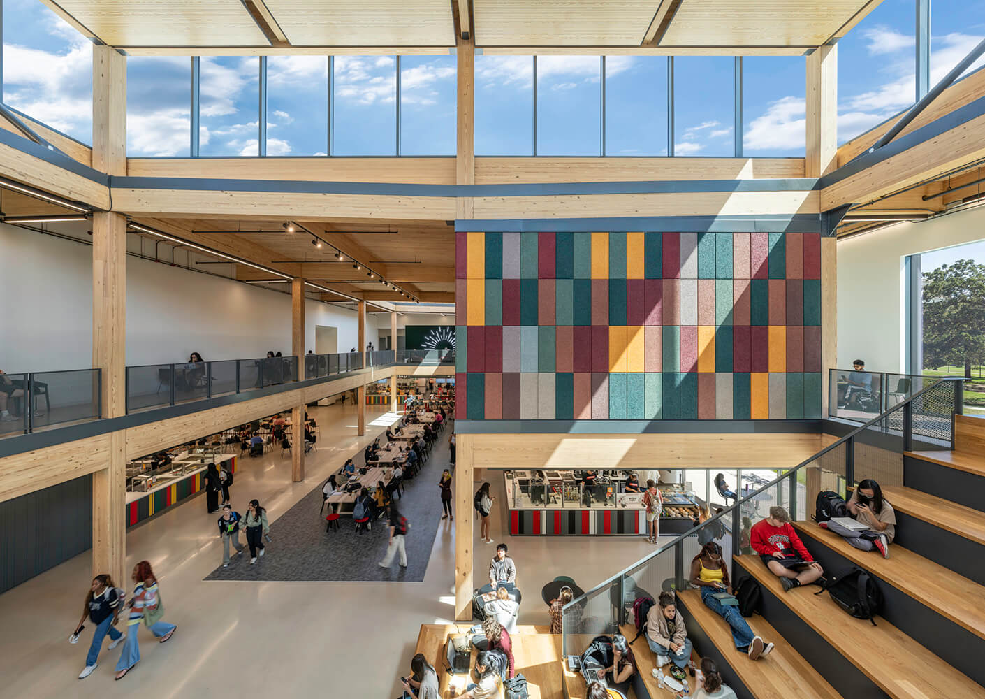 Modern open-space interior with students, colorful wall panels, and natural lighting.