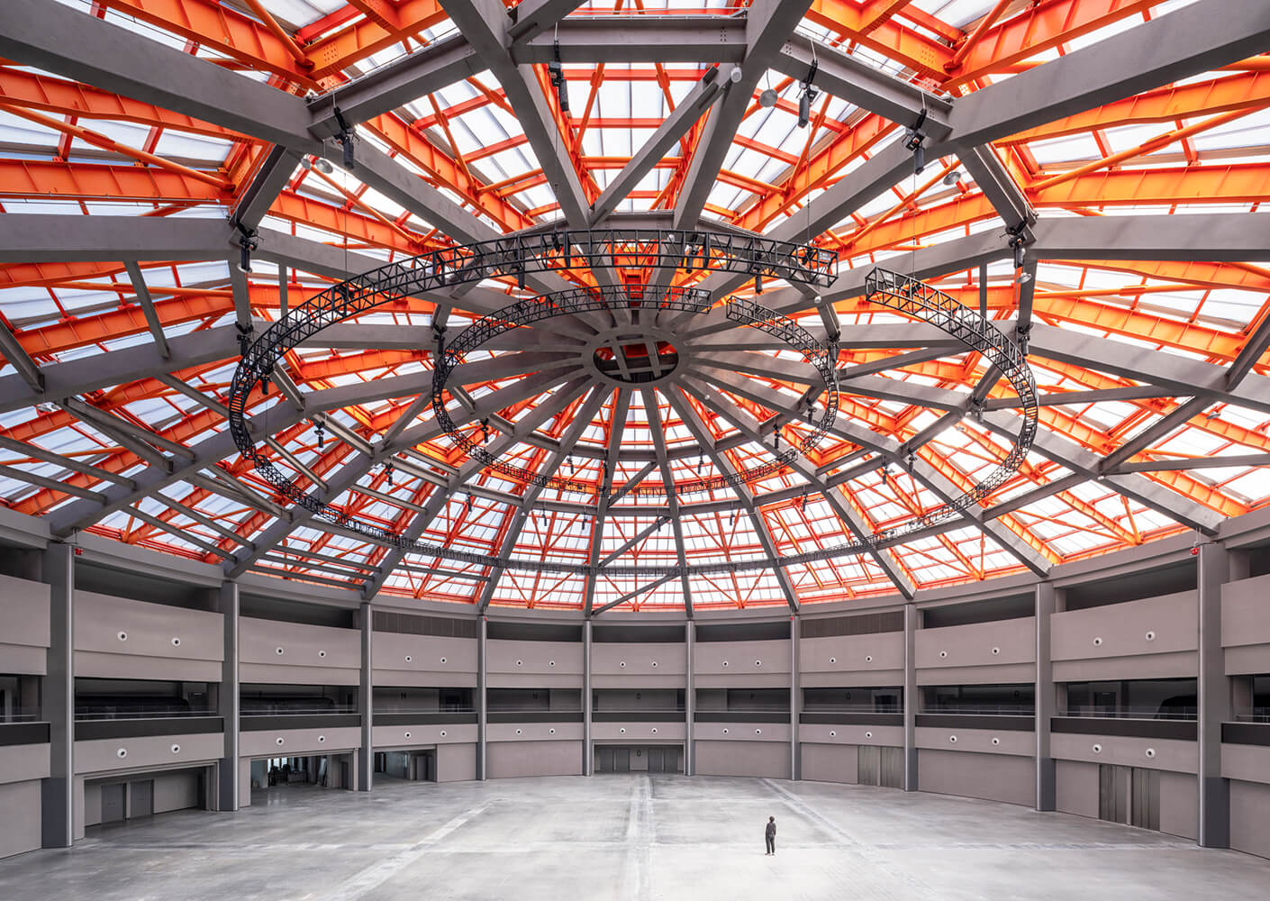 Spacious dome interior with geometric design and a lone person standing below.