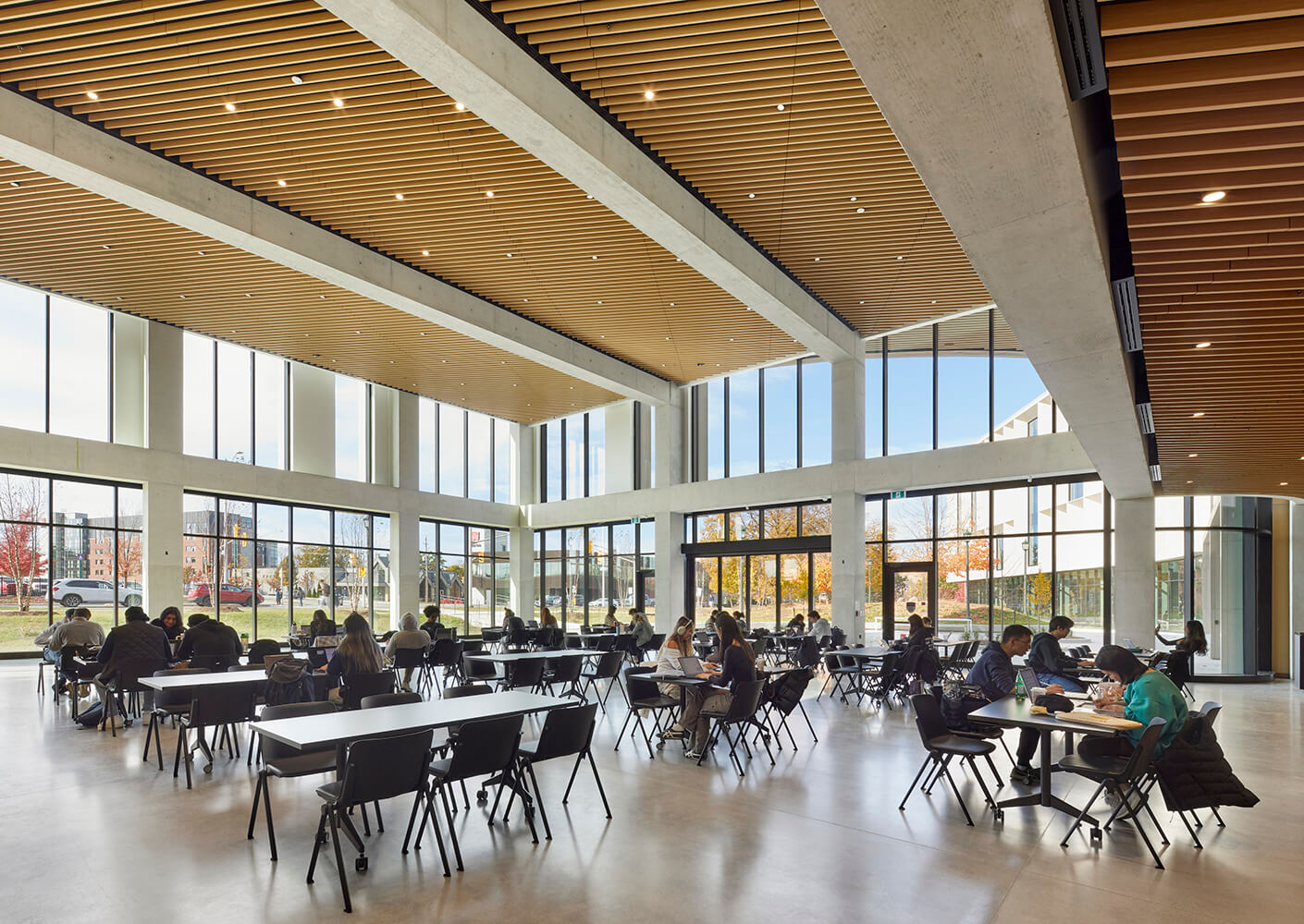 Modern study area with natural light and people at tables in a spacious building.