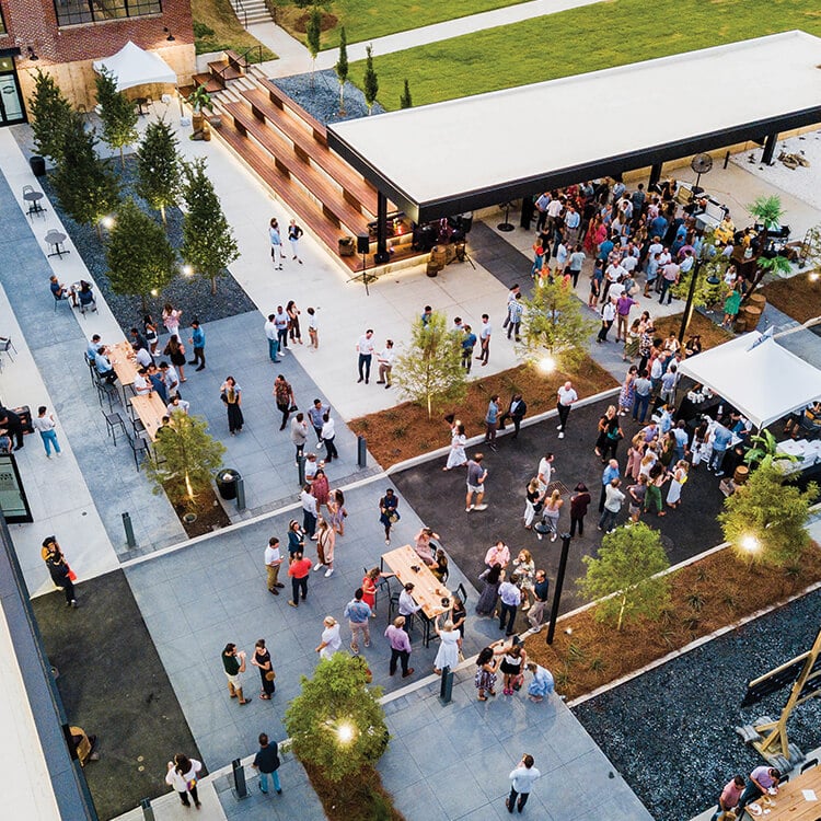 Aerial view of outdoor event with people gathering and socializing.