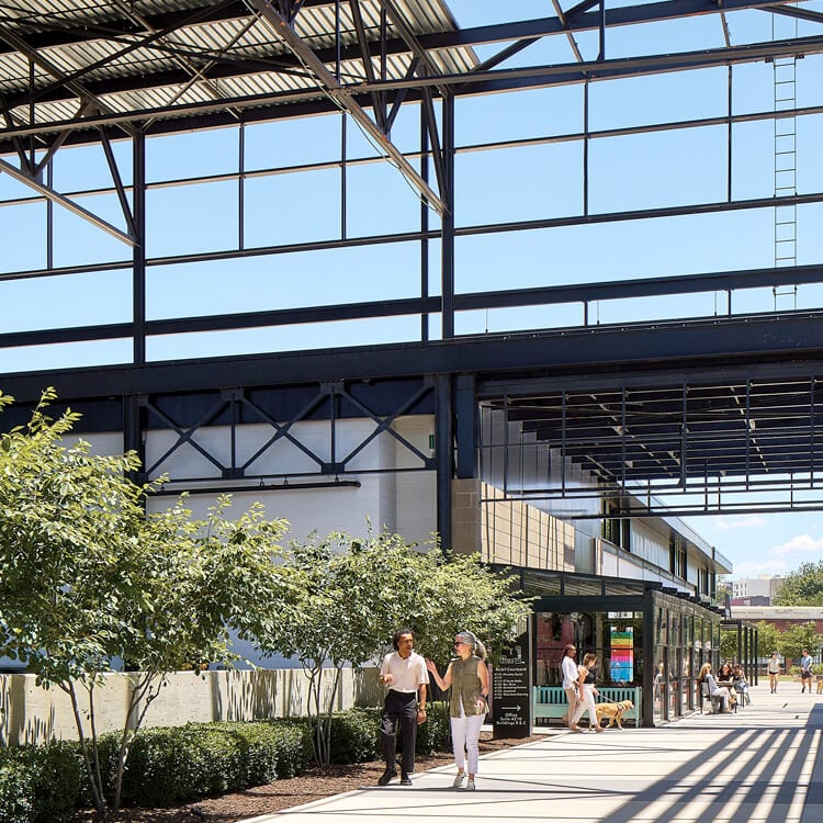 Open converted industrial space with walkway and people enjoying a sunny day.