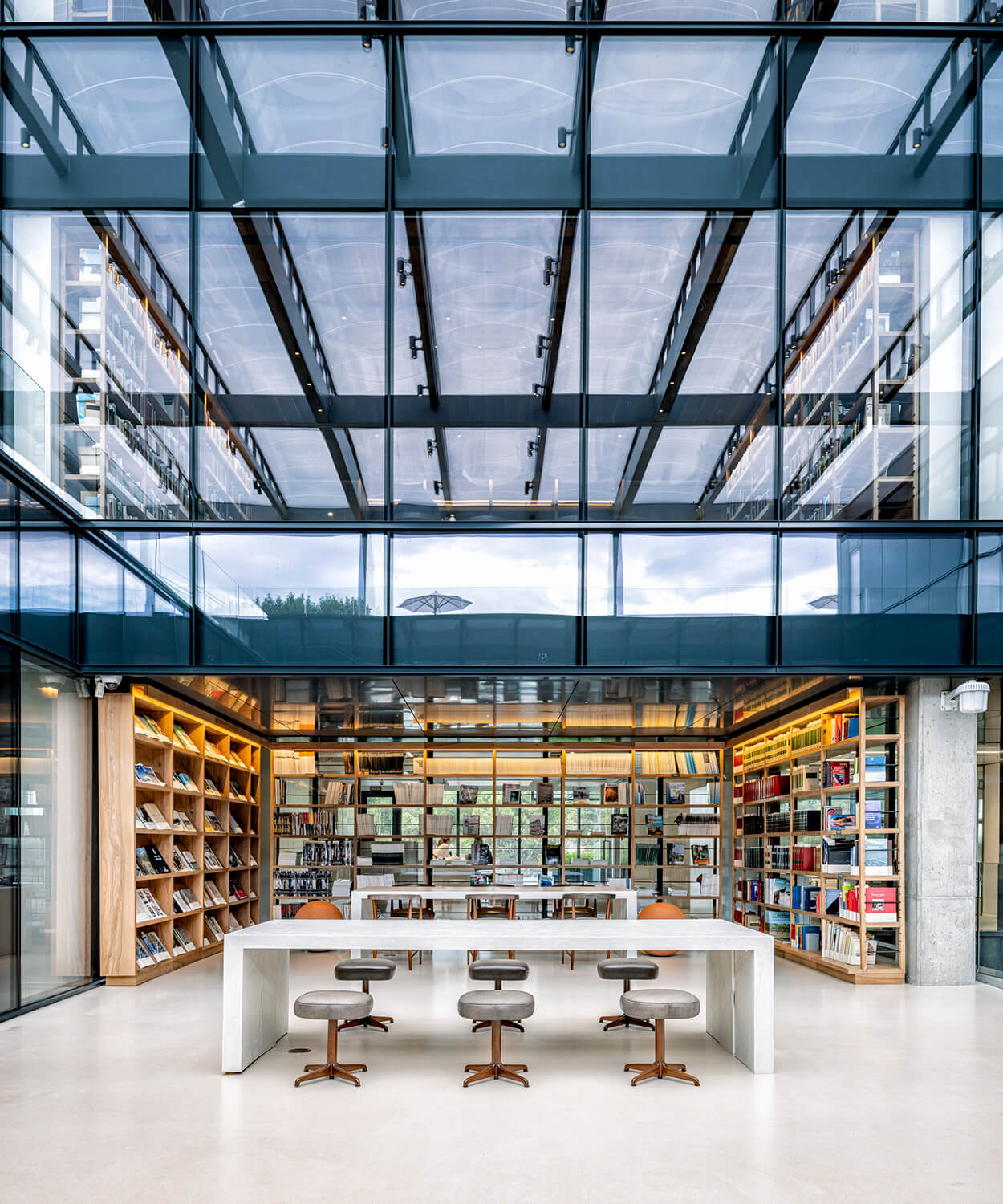 Modern library interior with bookshelves and glass ceiling.