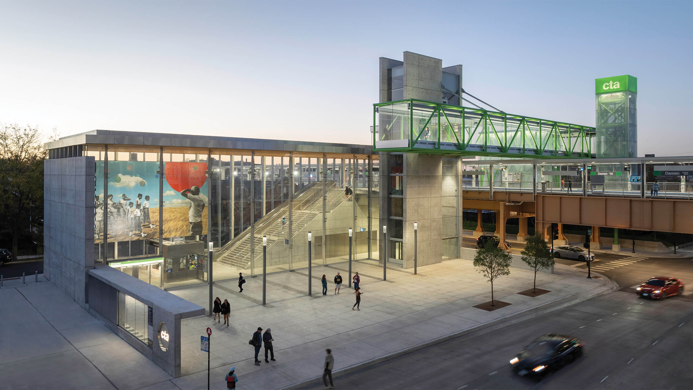 Modern transit station with glass architecture at dusk, featuring vibrant mural.