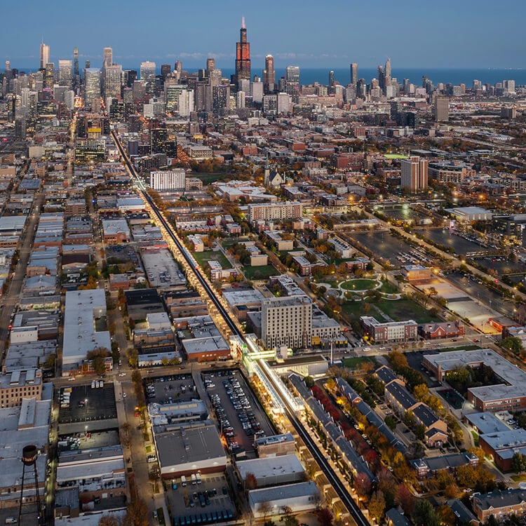Aerial view of city skyline at dusk with illuminated streets and buildings.