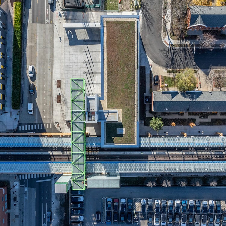 Aerial view of an urban green roof and street intersection with cars and train tracks.