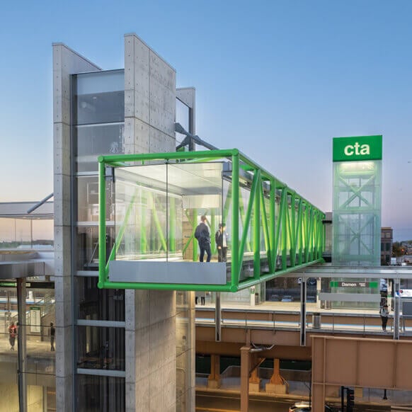 Modern public transit station with glass walkway and green structural details