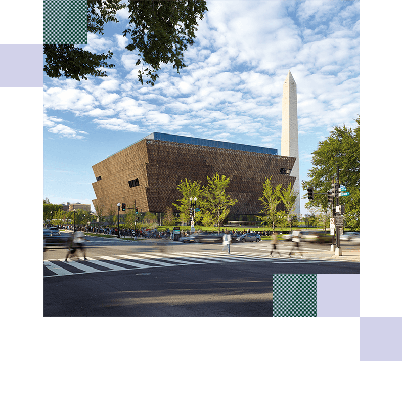 Modern museum and people crossing street, Washington Monument in background.