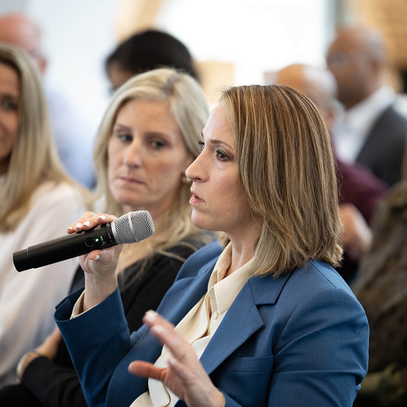 Yanel de Angel speaking into a microphone at a conference.