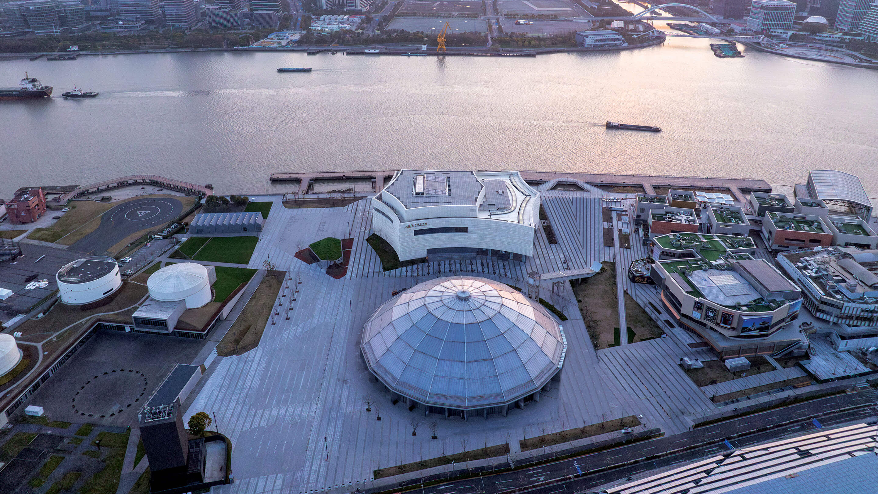 Aerial view of a waterfront modern architectural complex near a river.