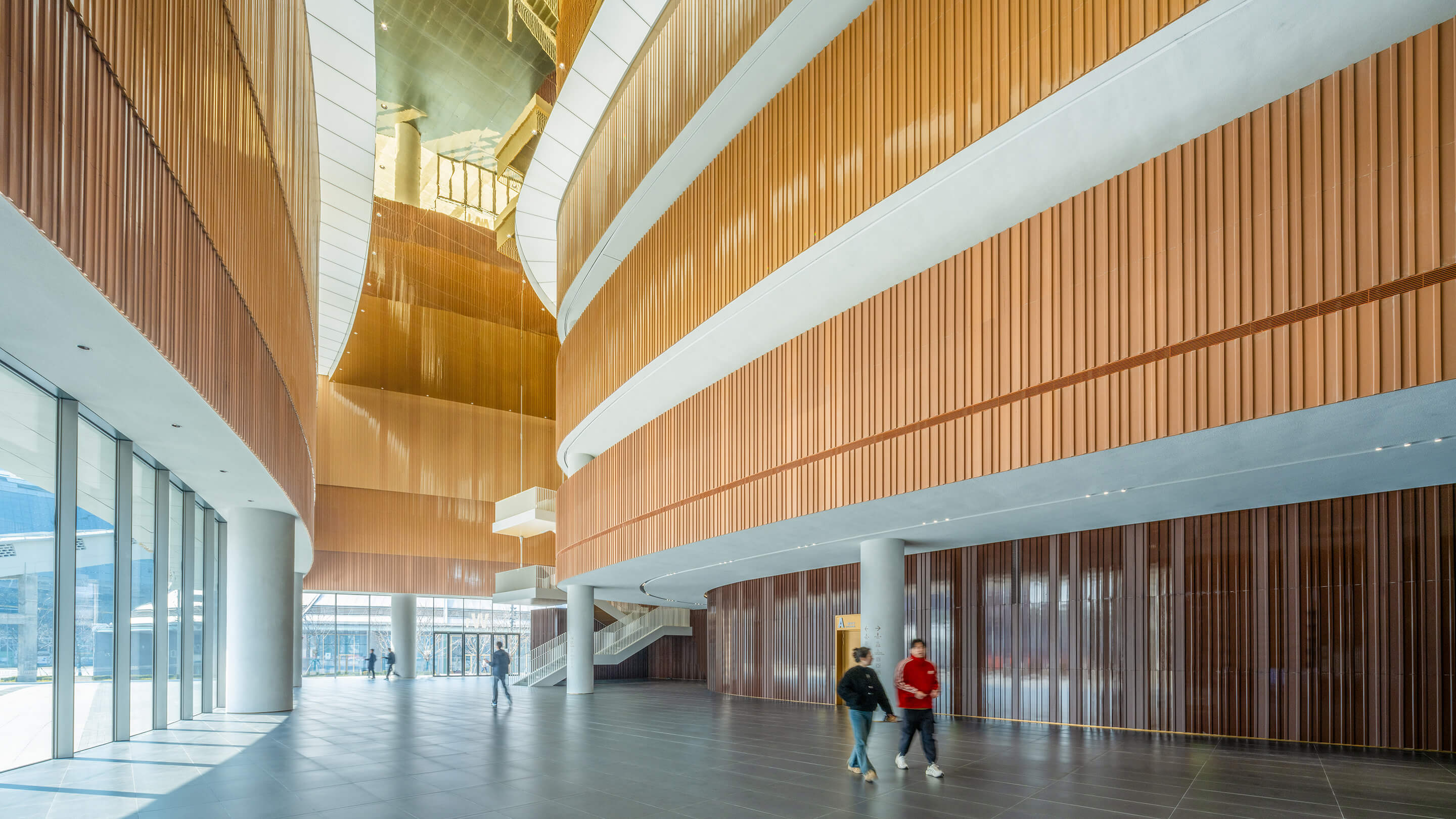 Modern architectural interior with high ceilings and curved wooden walls.