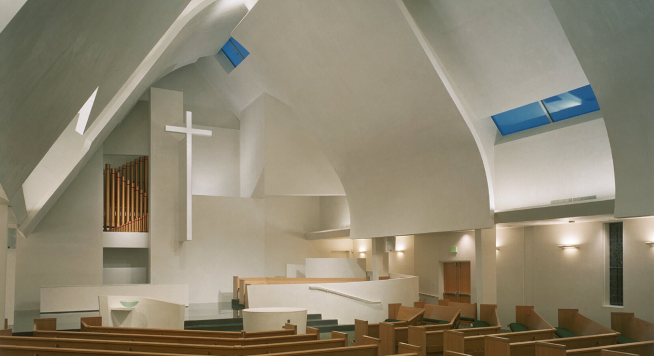 Modern church interior with cross and organ pipes.