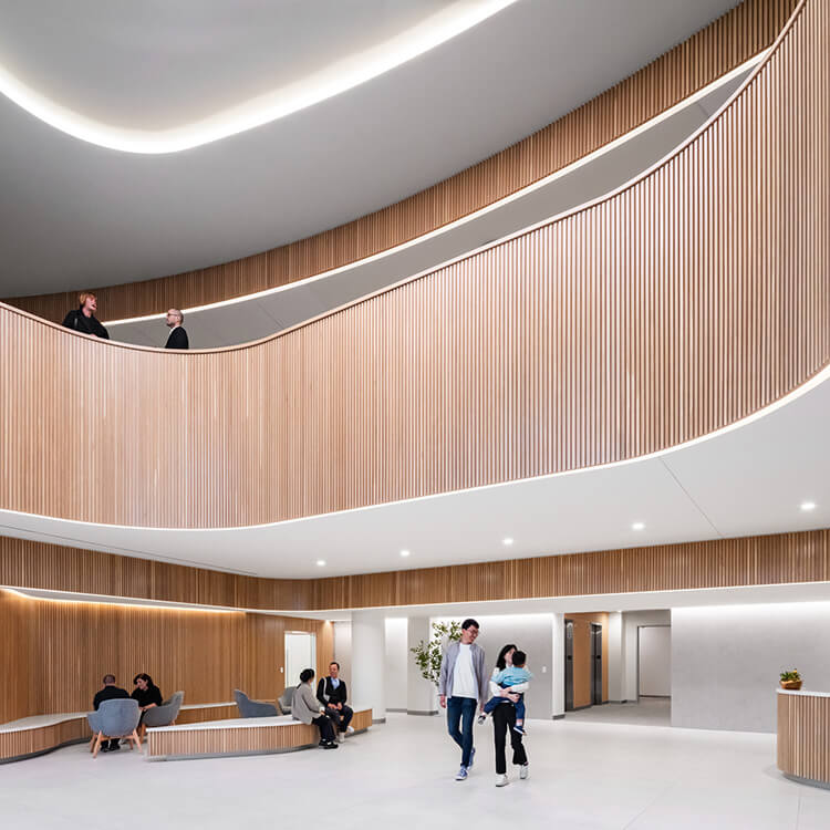 Modern interior with curved wooden design and people in a spacious lobby area.